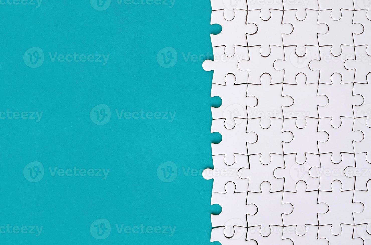 Fragment of a folded white jigsaw puzzle on the background of a blue plastic surface. Texture photo with copy space for text