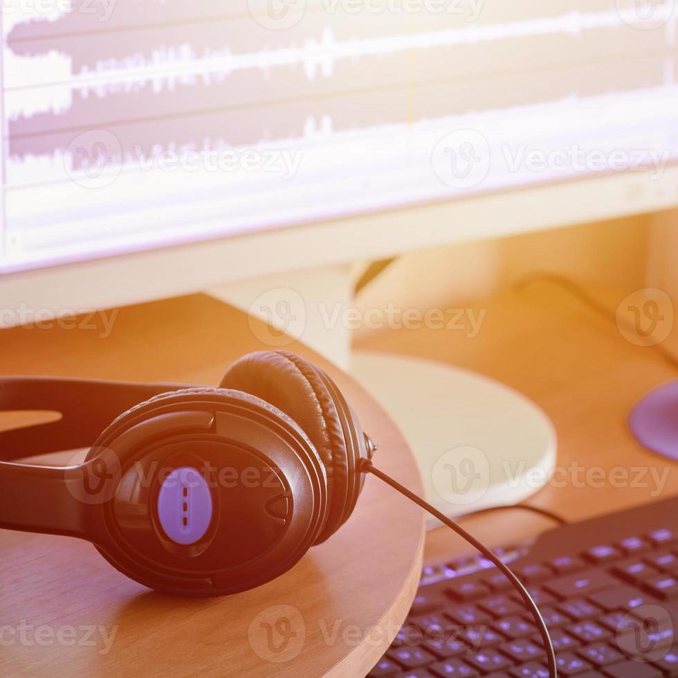 Big black headphones lie on the wooden desktop of the sound designer photo