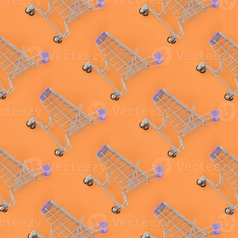 Shopping addiction, shopping lover or shopaholic concept. Many small empty shopping carts perform a pattern on a pastel colored paper background. Flat lay composition, top view photo
