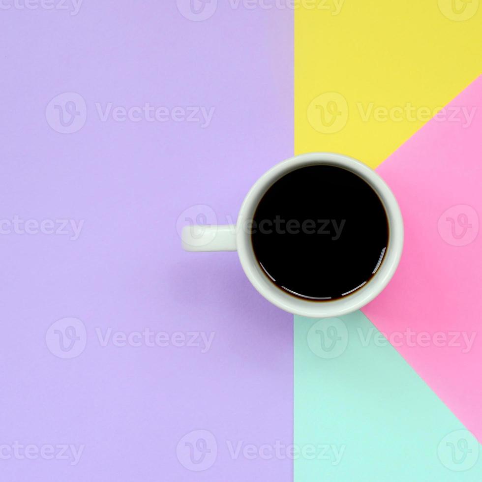 Small white coffee cup on texture background of fashion pastel blue, yellow, violet and pink colors paper in minimal concept photo