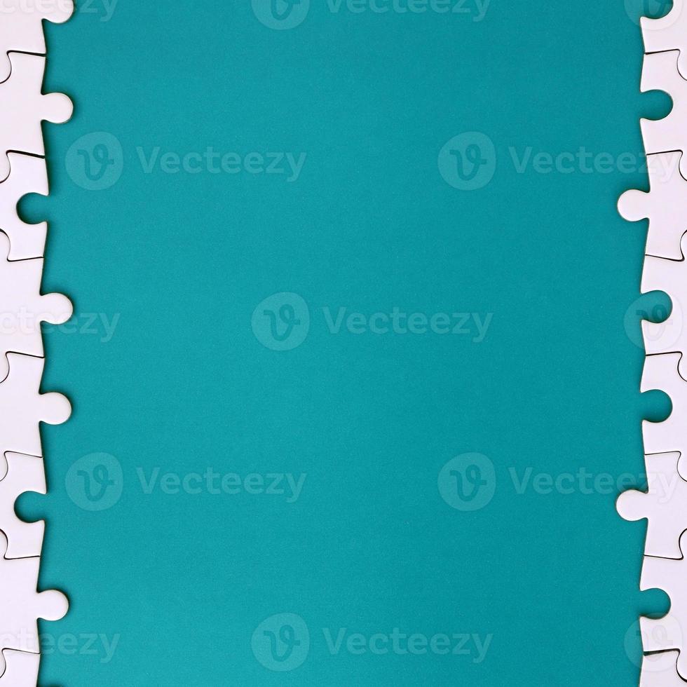 Fragment of a folded white jigsaw puzzle on the background of a blue plastic surface. Texture photo with copy space for text