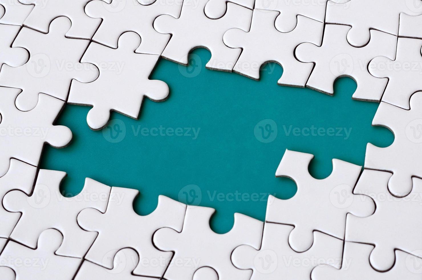 Close-up texture of a white jigsaw puzzle in assembled state with missing elements forming a blue pad for text. Copy space photo