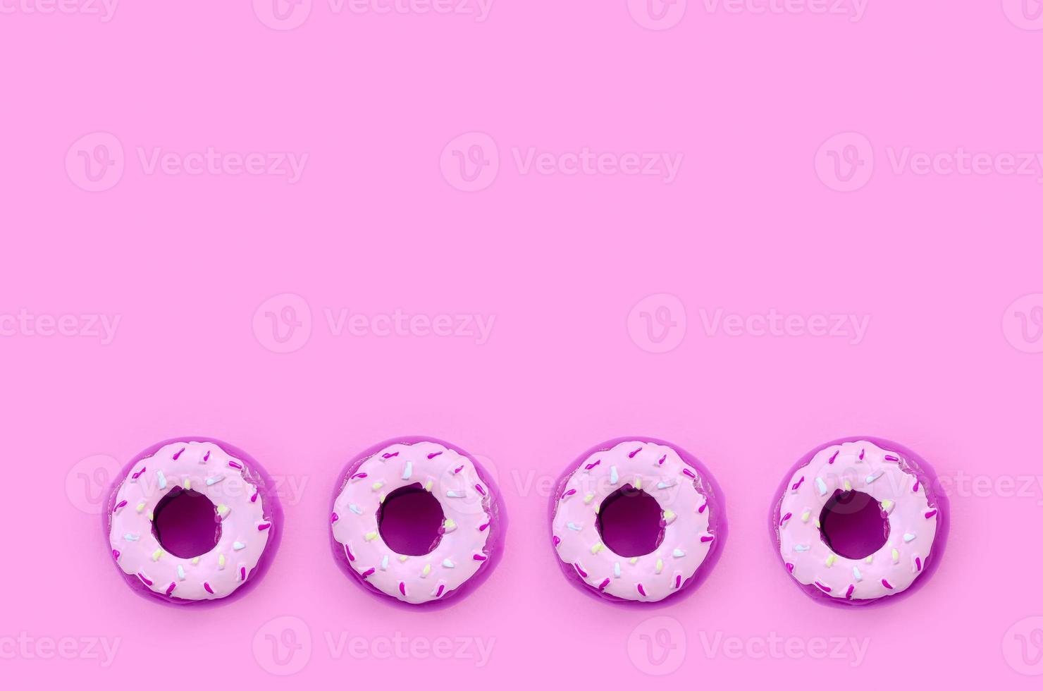 Many small plastic donuts lies on a pastel colorful background. Flat lay minimal pattern. Top view photo