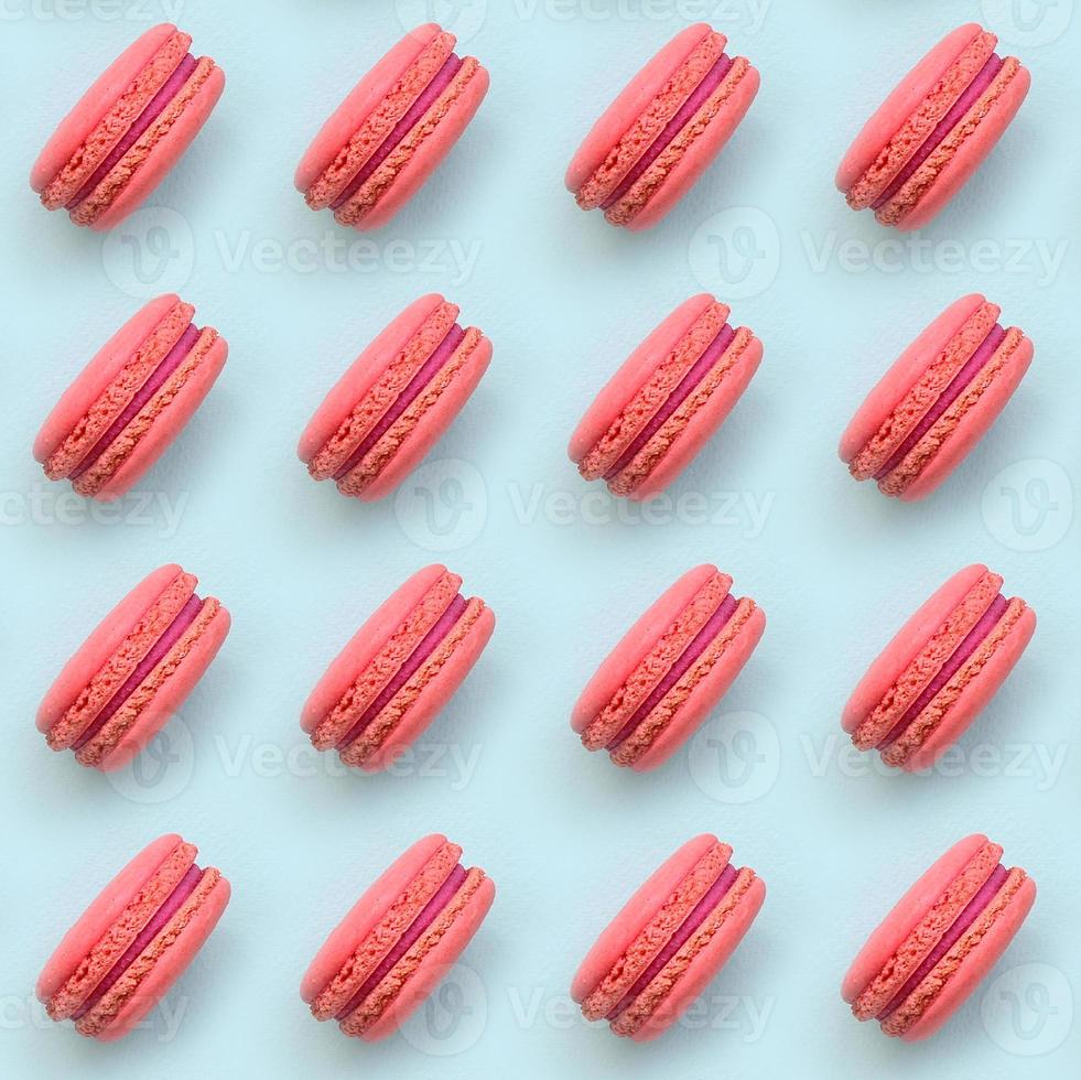Pink dessert cake macaron or macaroon on trendy pastel blue background top view. Flat lay pattern composition photo