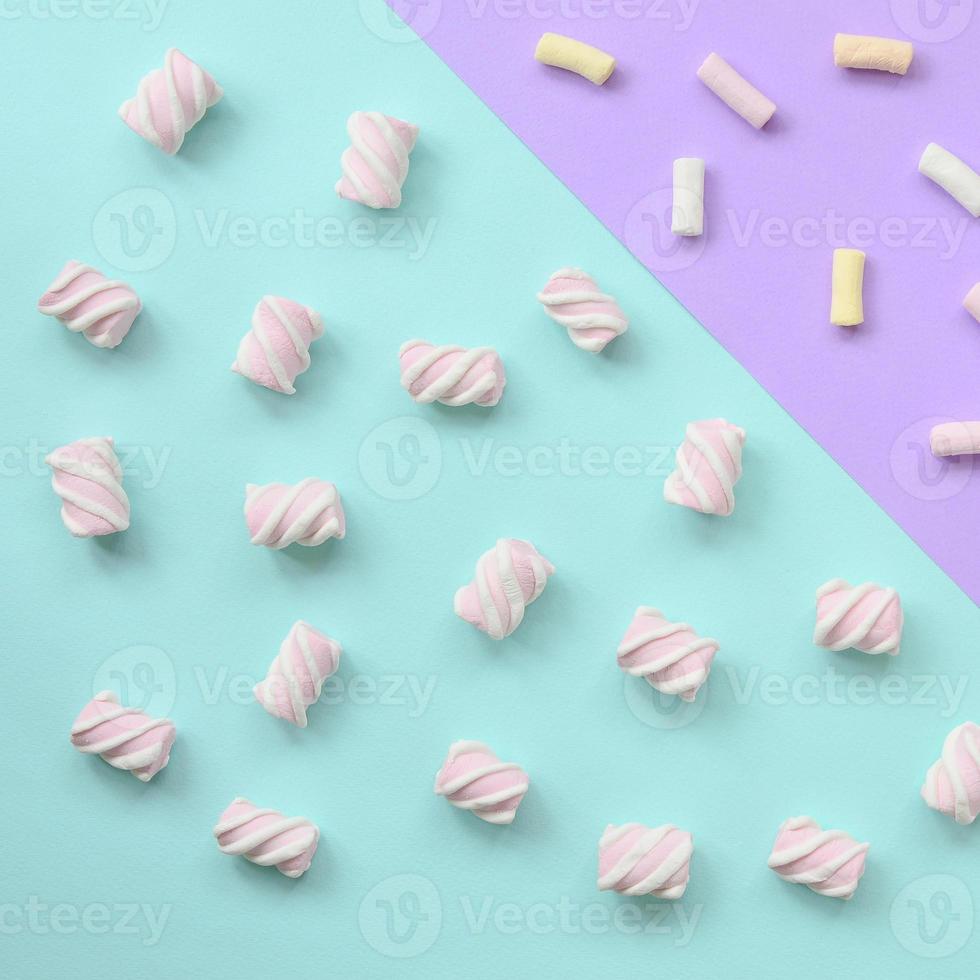 Colorful marshmallow laid out on violet and blue paper background. pastel creative textured pattern. minimal photo