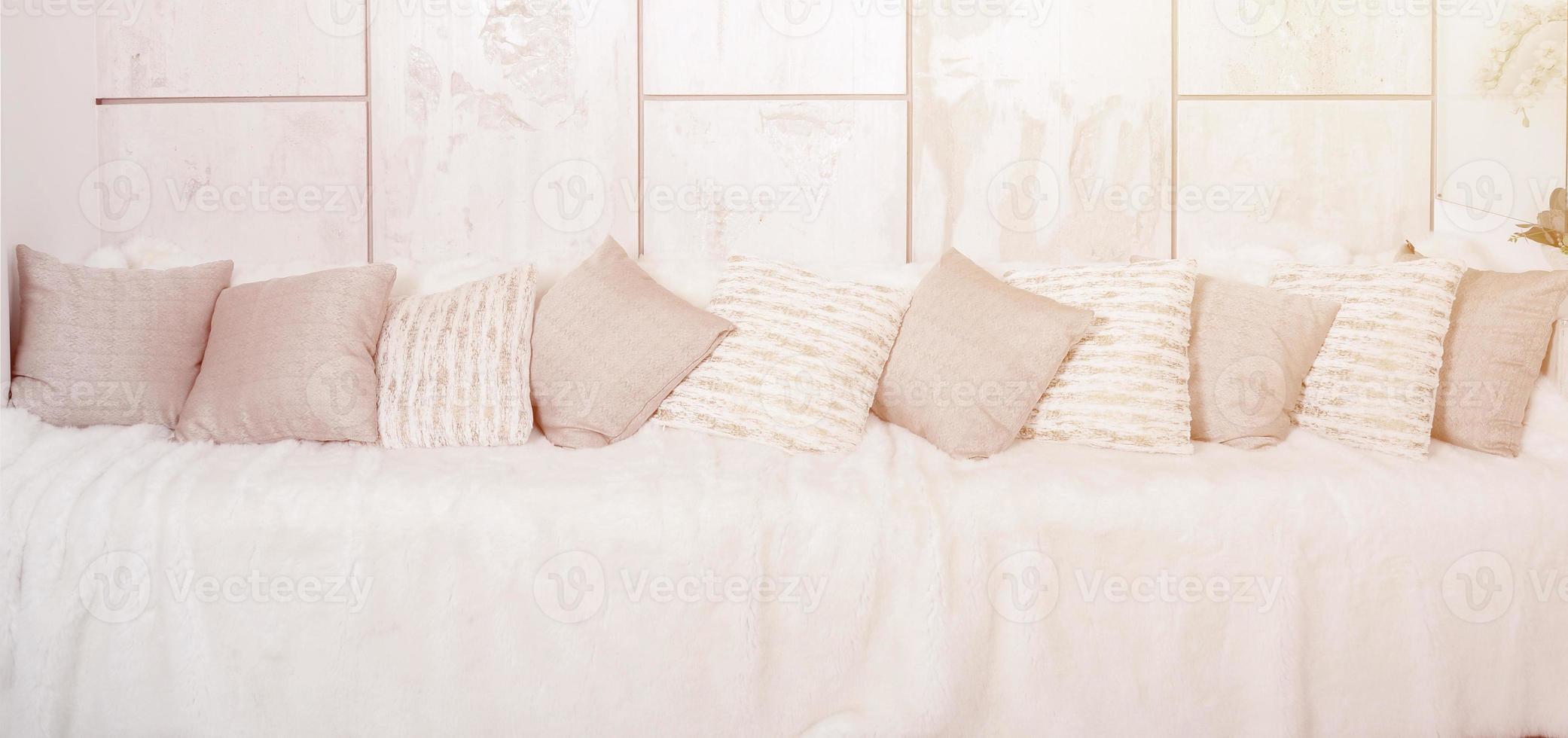muchas almohadas yacen en el sofá, que está cubierto con un gran velo de felpa contra el fondo de una pared de mármol foto