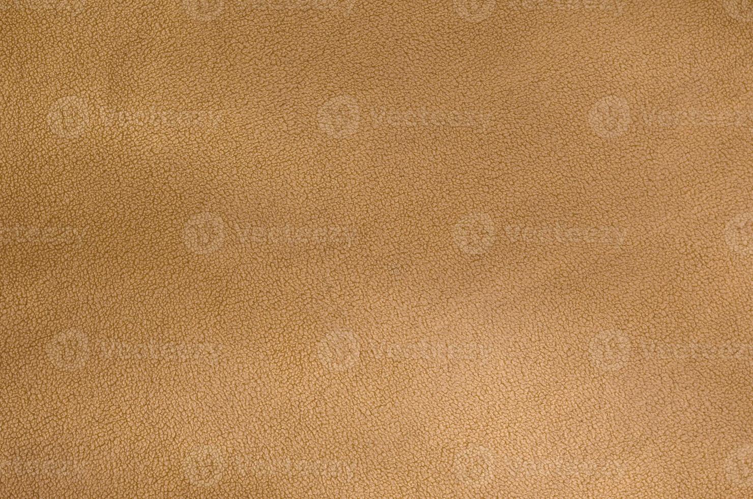 The blanket of furry orange fleece fabric. A background texture of light orange soft plush fleece material photo