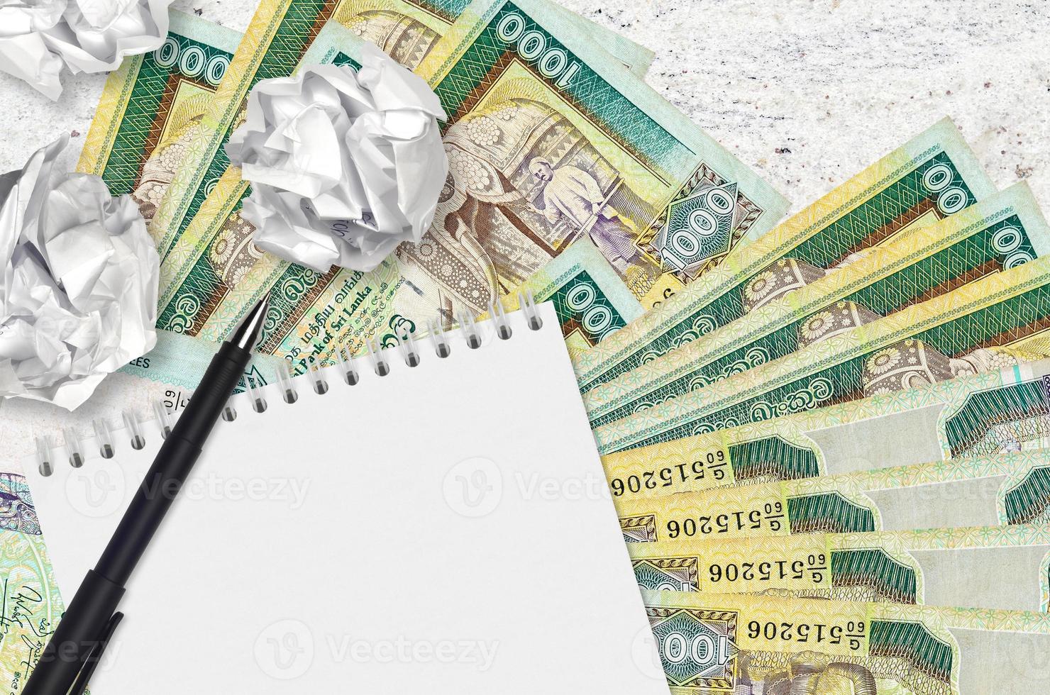 1000 Sri Lankan rupees bills and balls of crumpled paper with blank notepad. Bad ideas or less of inspiration concept. Searching ideas for investment photo