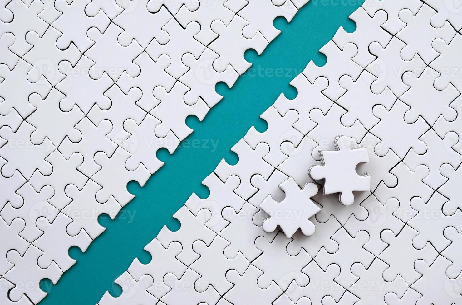 The blue path is laid on the platform of a white folded jigsaw puzzle. The missing elements of the puzzle are stacked nearby. Texture image with space for text photo