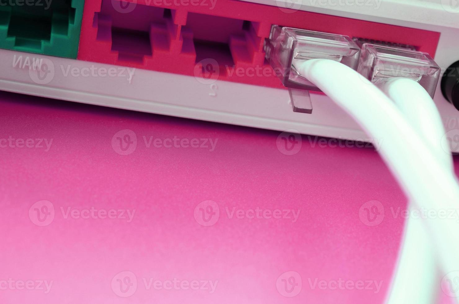 The Internet cable plugs are connected to the Internet router, which lies on a bright pink background. Items required for Internet photo