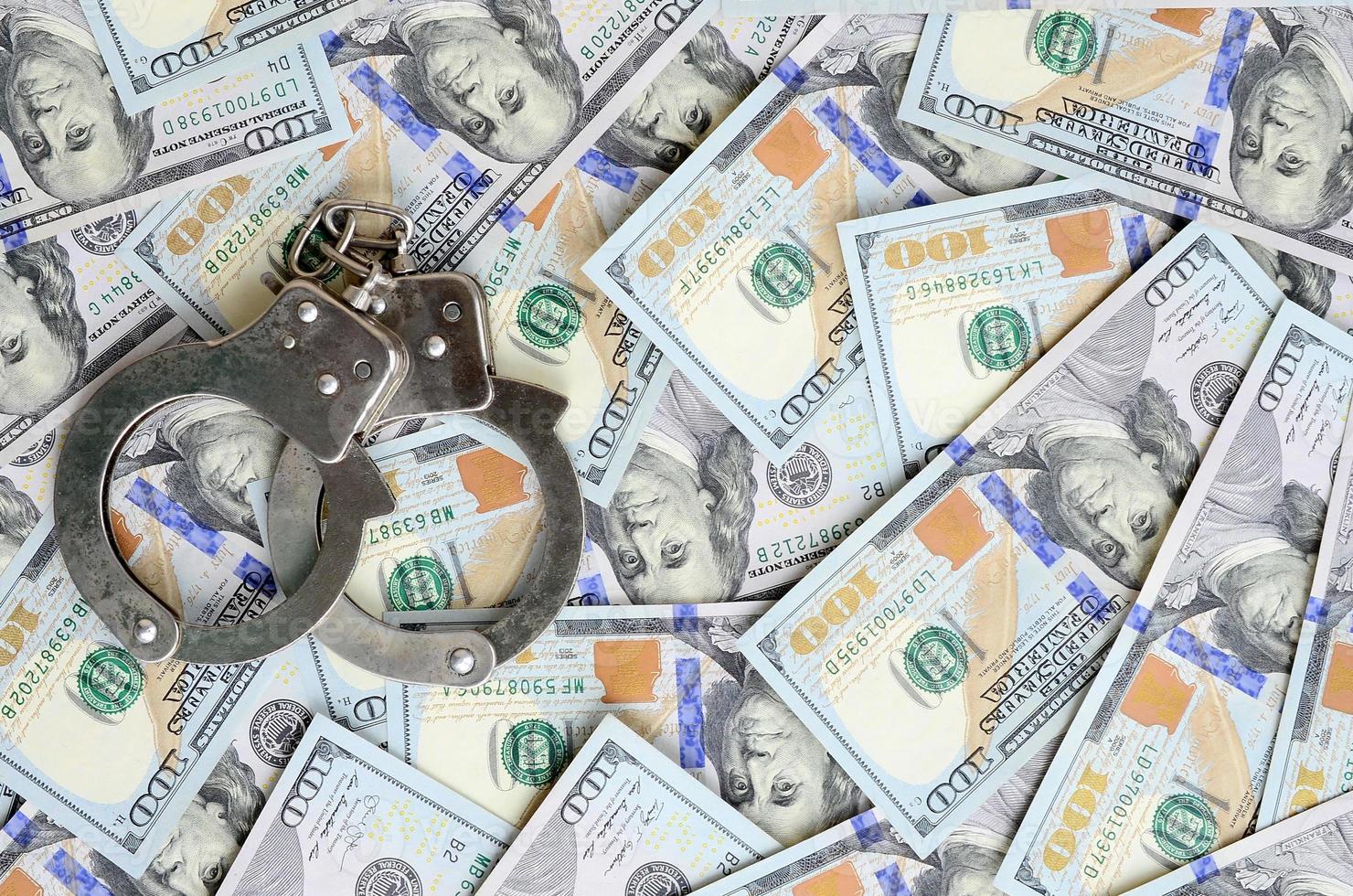 Silver police handcuffs lies on a many dollar bills photo