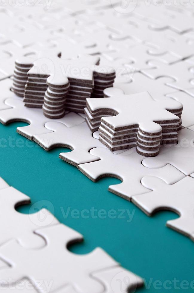 The blue path is laid on the platform of a white folded jigsaw puzzle. The missing elements of the puzzle are stacked nearby. Texture image with space for text photo