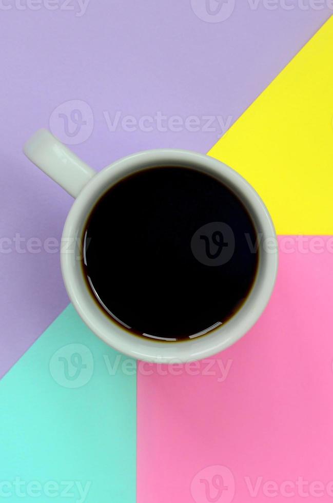 Small white coffee cup on texture background of fashion pastel blue, yellow, violet and pink colors paper in minimal concept photo