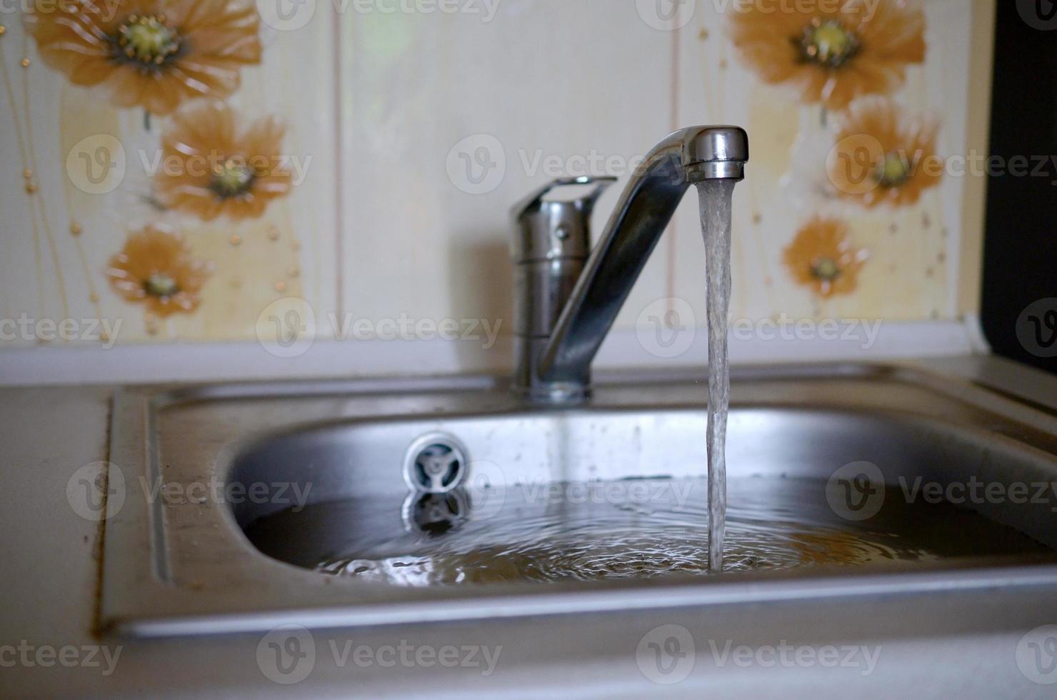 Stainless steel sink plug hole close up full of water and particles of food photo