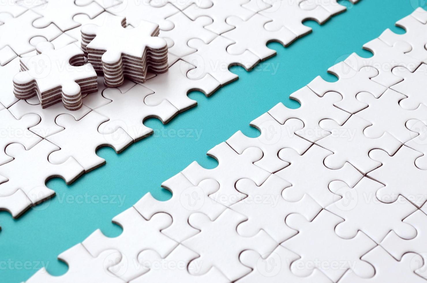 The blue path is laid on the platform of a white folded jigsaw puzzle. The missing elements of the puzzle are stacked nearby. Texture image with space for text photo