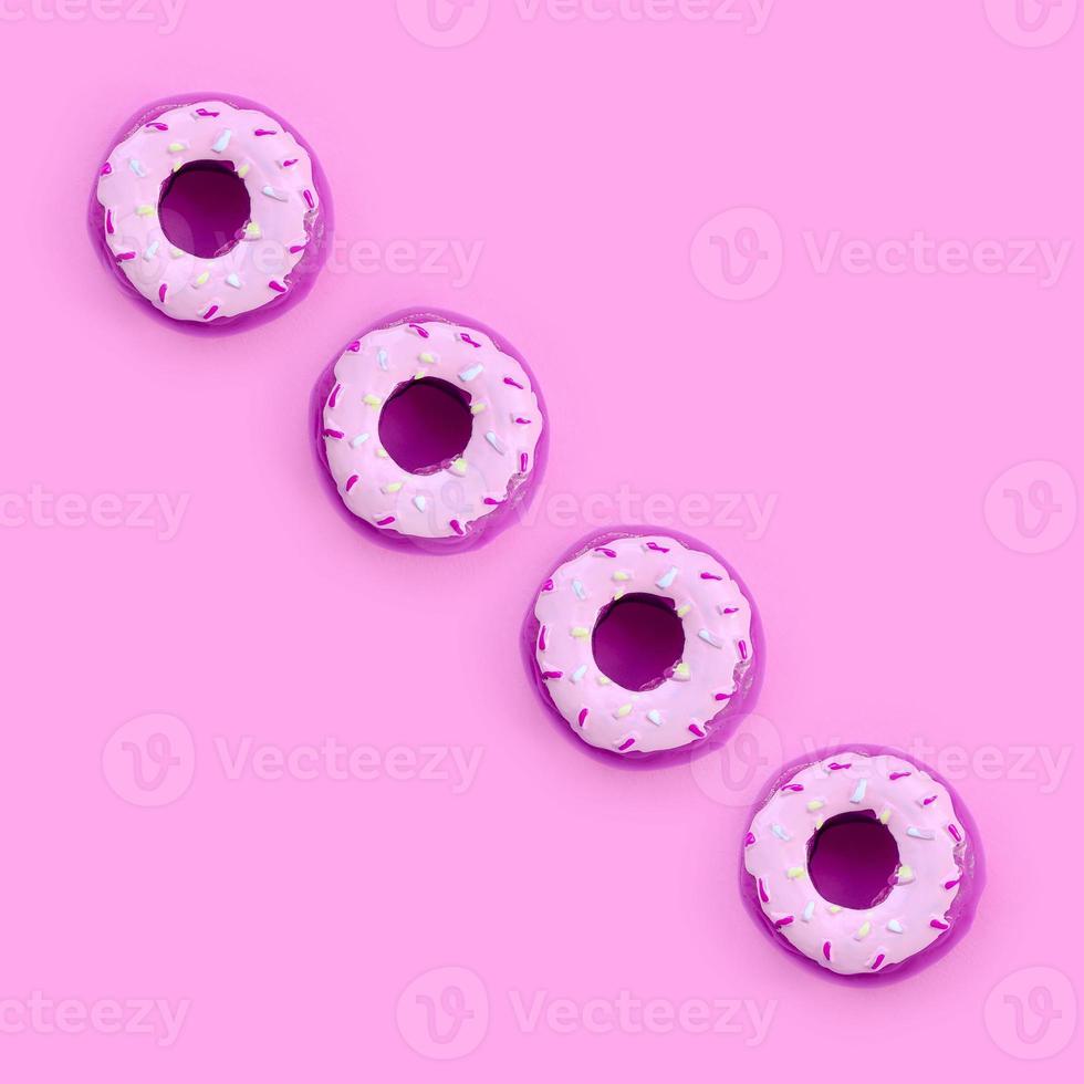 Many small plastic donuts lies on a pastel colorful background. Flat lay minimal pattern. Top view photo