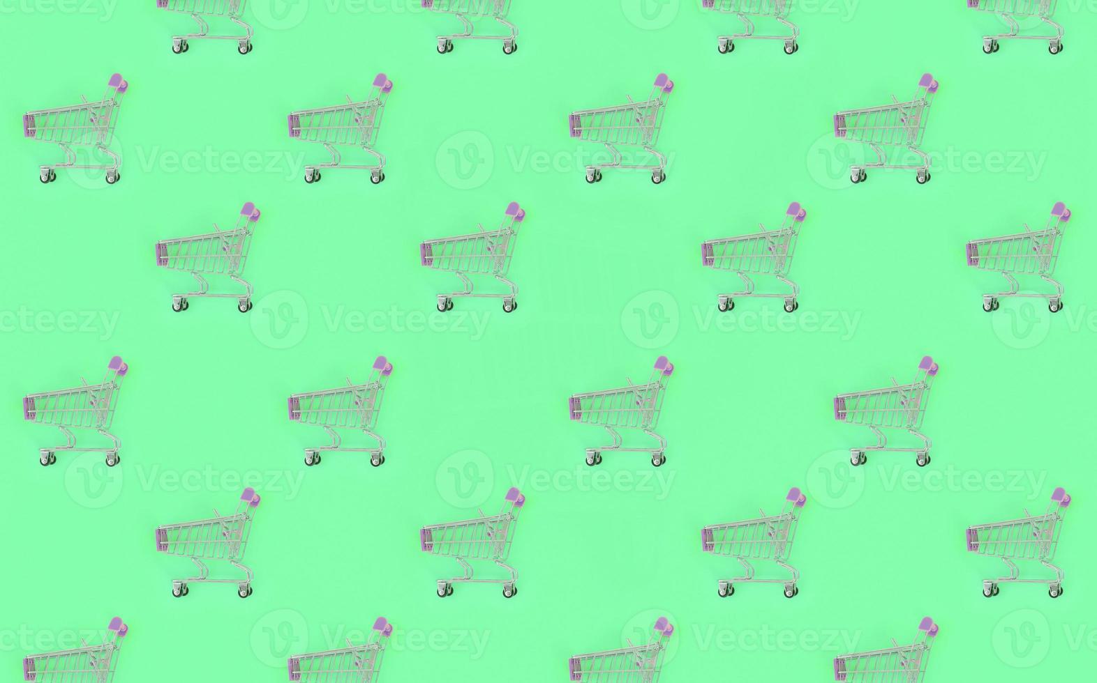 Shopping addiction, shopping lover or shopaholic concept. Many small empty shopping carts perform a pattern on a pastel colored paper background. Flat lay composition, top view photo