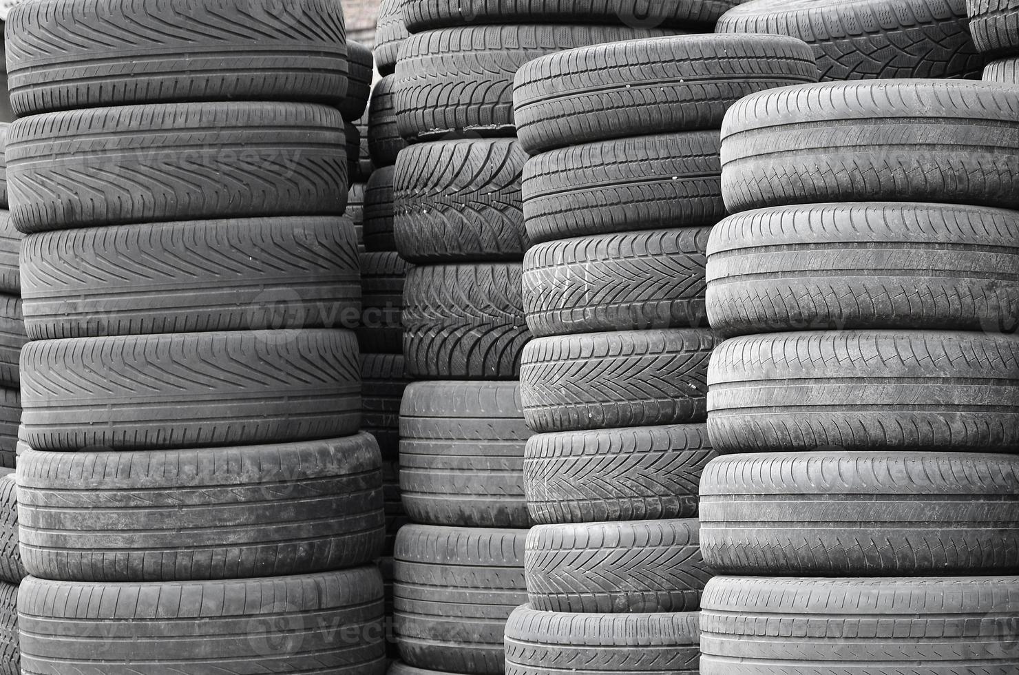 Old used tires stacked with high piles in secondary car parts shop garage photo