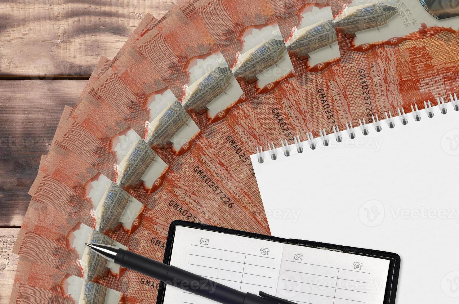 50 Canadian dollars bills fan and notepad with contact book and black pen. Concept of financial planning and business strategy photo