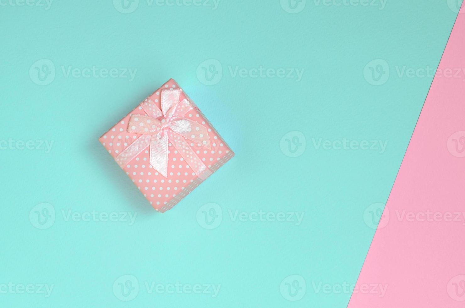 Small pink gift box lie on texture background of fashion pastel blue and pink colors paper in minimal concept photo