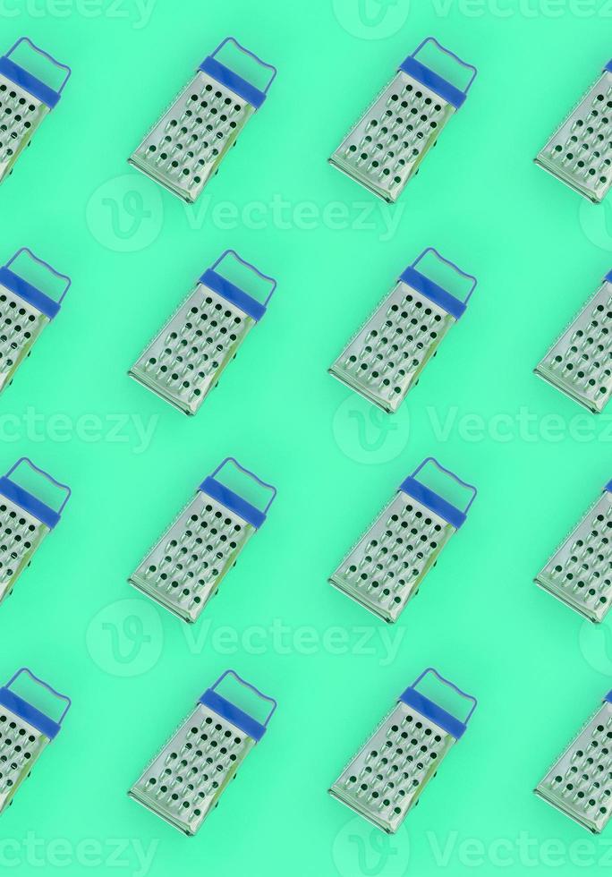 Small stainless steel graters lies on a pastel colored paper. Kitchen accessories. Tools for cooking. Flat lay top view photo