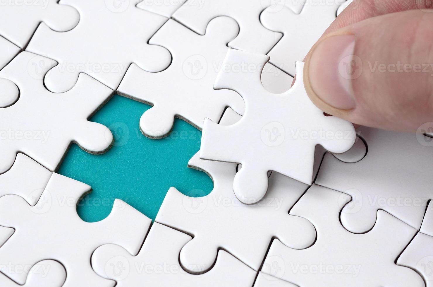 The human hand fills the last missing elements of the surface from the jigsaw puzzle. The concept of the completion of the initiated cases photo