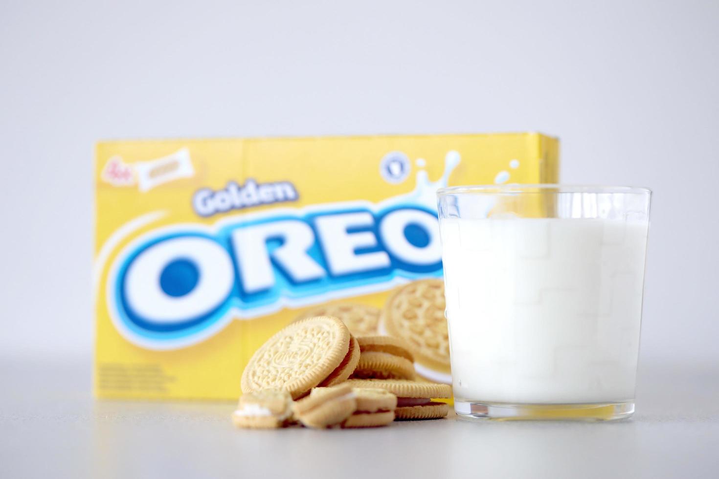 TERNOPIL, UKRAINE - MAY 28, 2022 Oreo golden crispy cookies with glass of milk on white background. The brand Oreo is owned by company Mondelez international photo