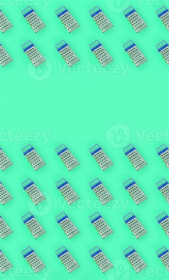 Small stainless steel graters lies on a pastel colored paper. Kitchen accessories. Tools for cooking. Flat lay top view photo