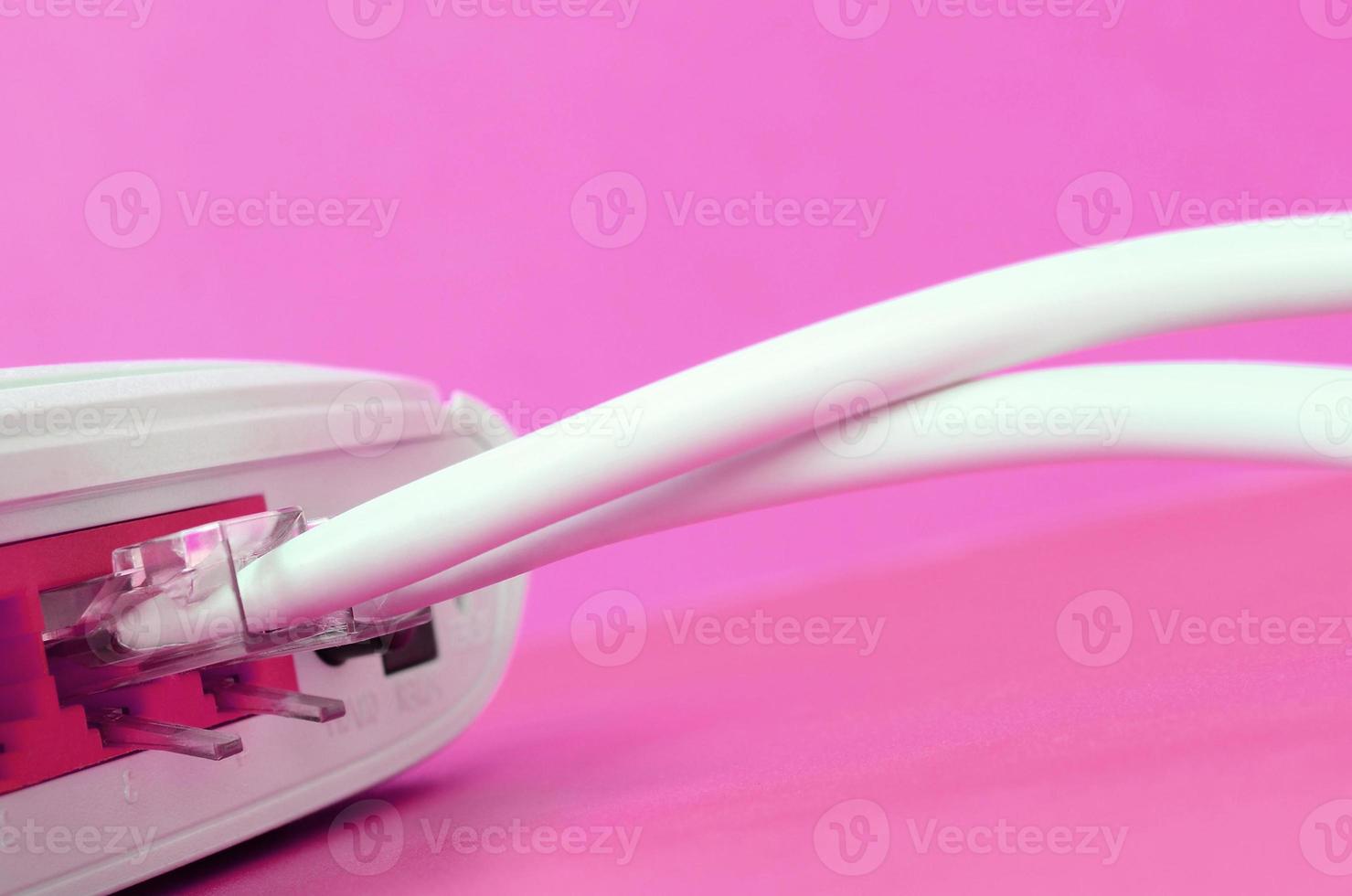 The Internet cable plugs are connected to the Internet router, which lies on a bright pink background. Items required for Internet photo