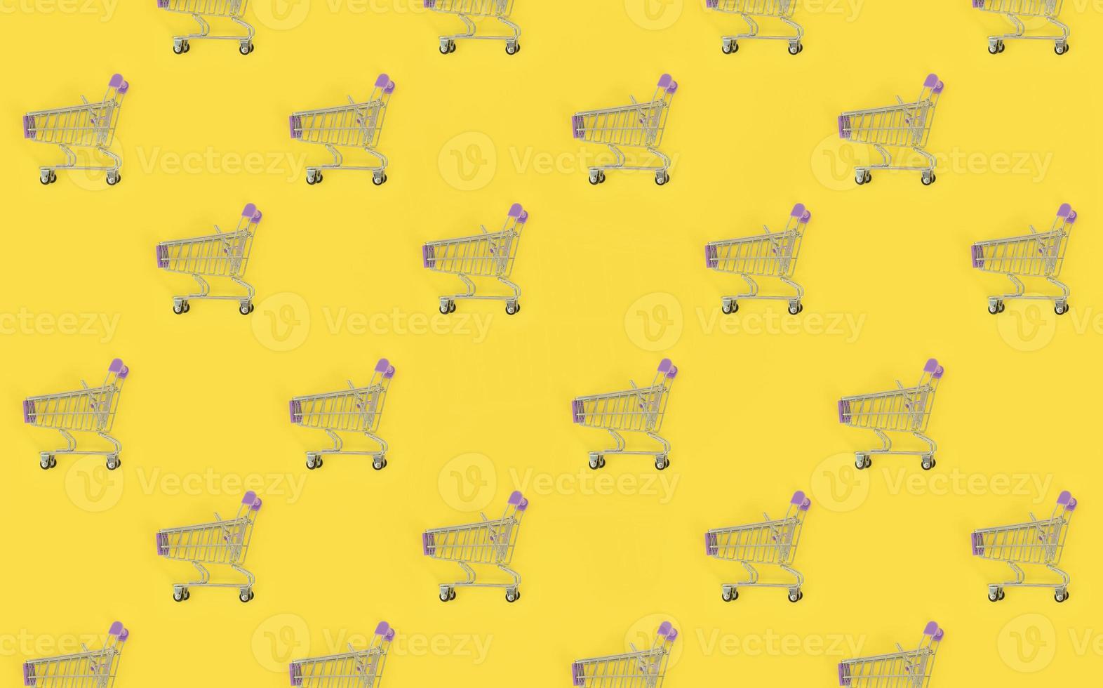 Shopping addiction, shopping lover or shopaholic concept. Many small empty shopping carts perform a pattern on a pastel colored paper background. Flat lay composition, top view photo