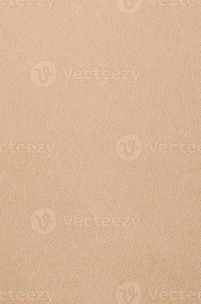 The blanket of furry orange fleece fabric. A background texture of light orange soft plush fleece material photo