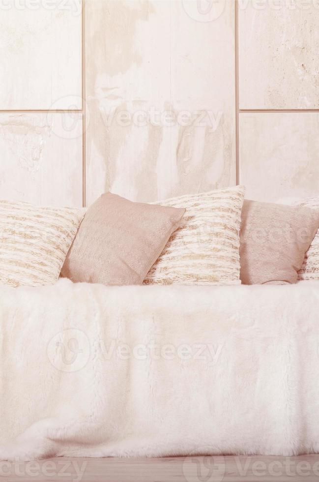 Many pillows lie on the couch, which is covered with a large plush veil against the background of a marble wall photo