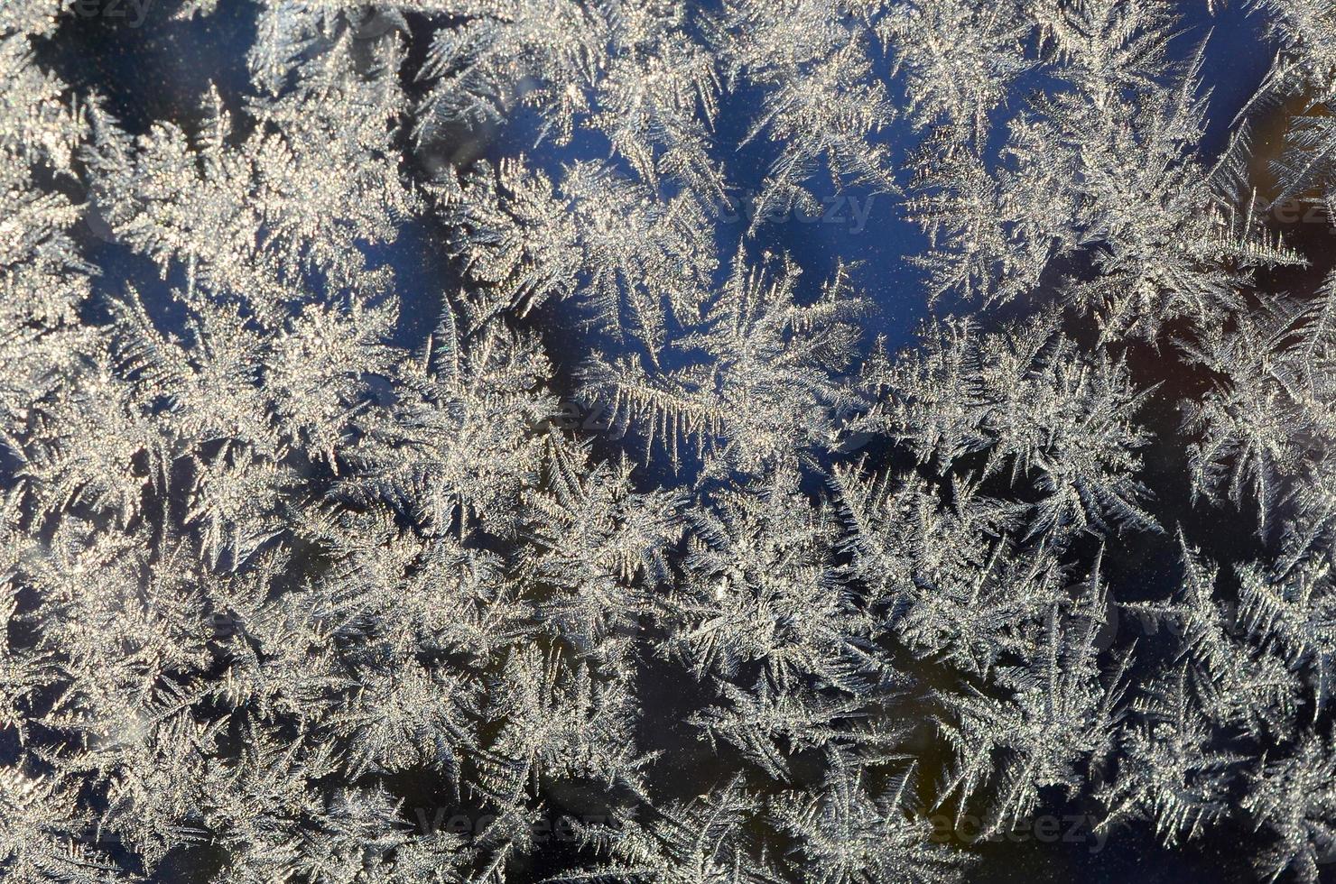 Snowflakes frost rime macro on window glass pane photo