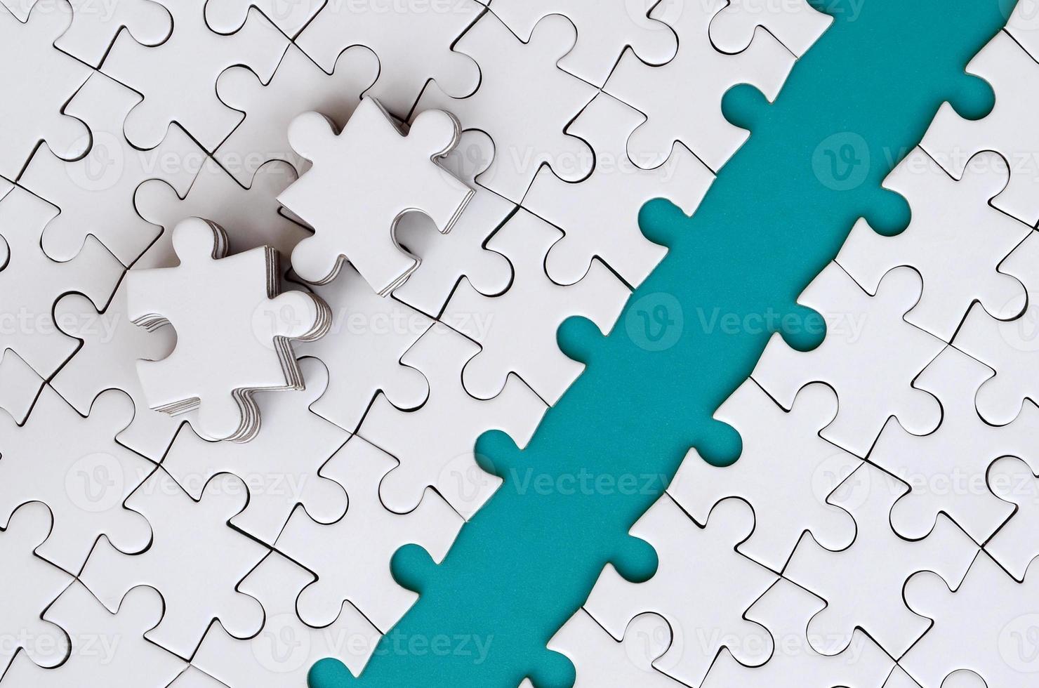 The blue path is laid on the platform of a white folded jigsaw puzzle. The missing elements of the puzzle are stacked nearby. Texture image with space for text photo