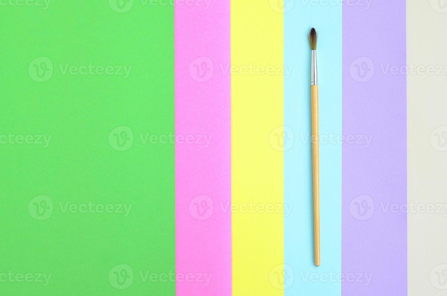 A new paint brush lie on texture background of fashion pastel pink, blue, green, yellow, violet and beige colors paper in minimal concept. Abstract trendy pattern photo