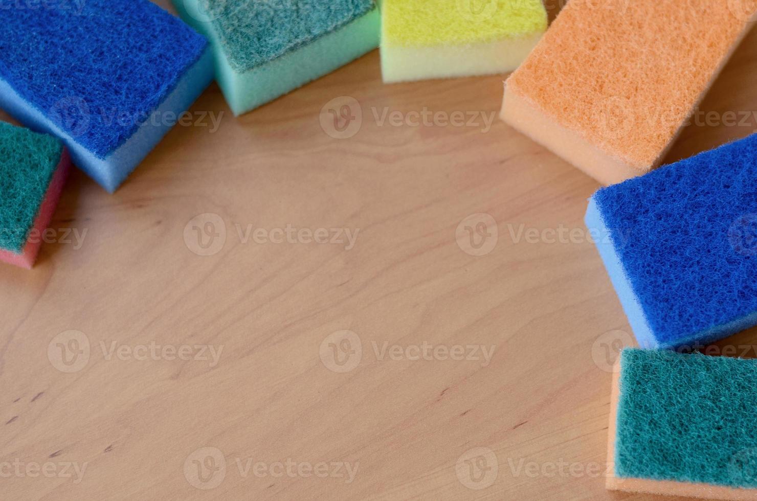 A few kitchen sponges lie on a wooden kitchen countertop. Colorful objects for washing dishes and cleaning in the house are ready for use photo