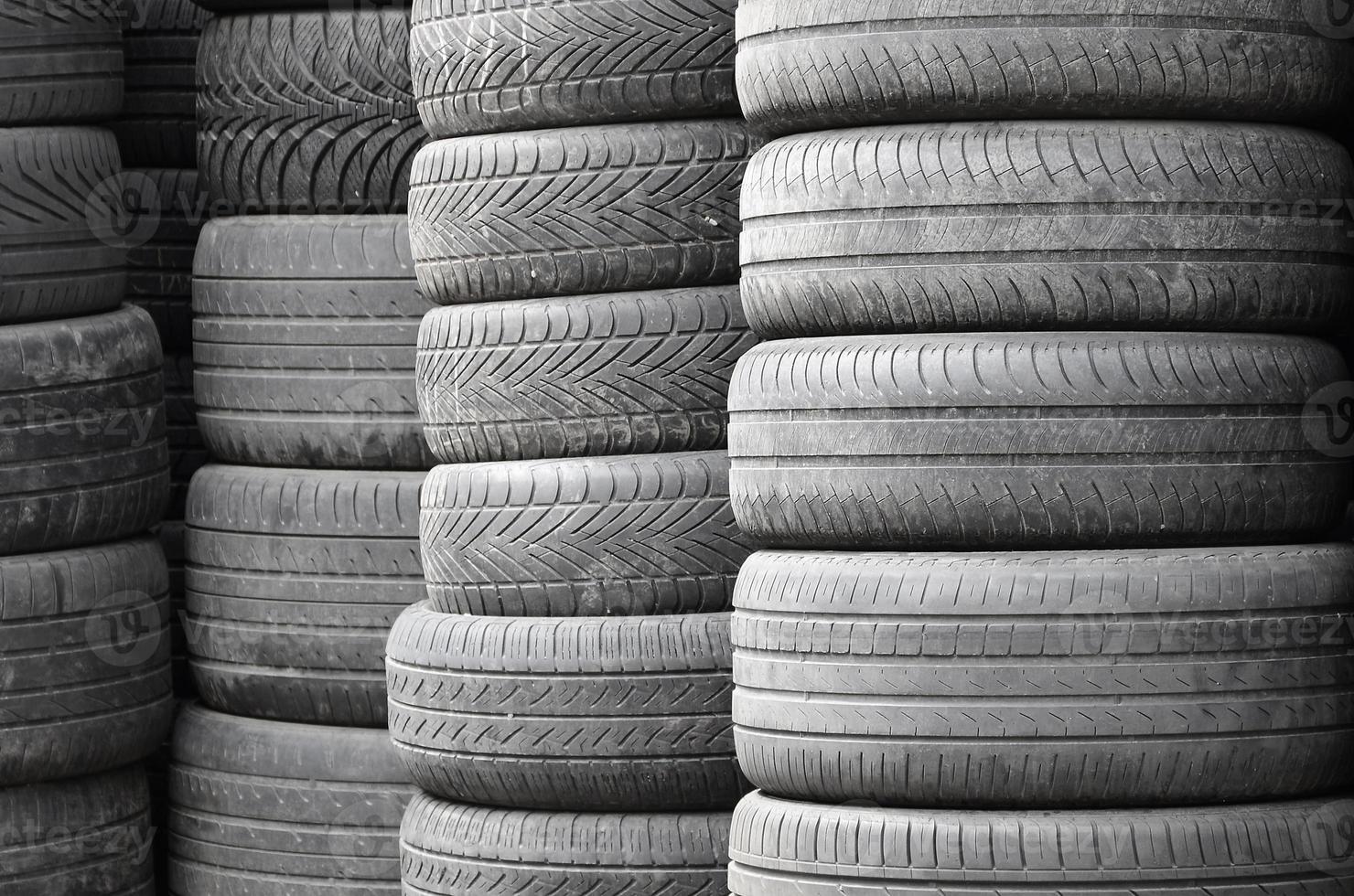 Old used tires stacked with high piles in secondary car parts shop garage photo