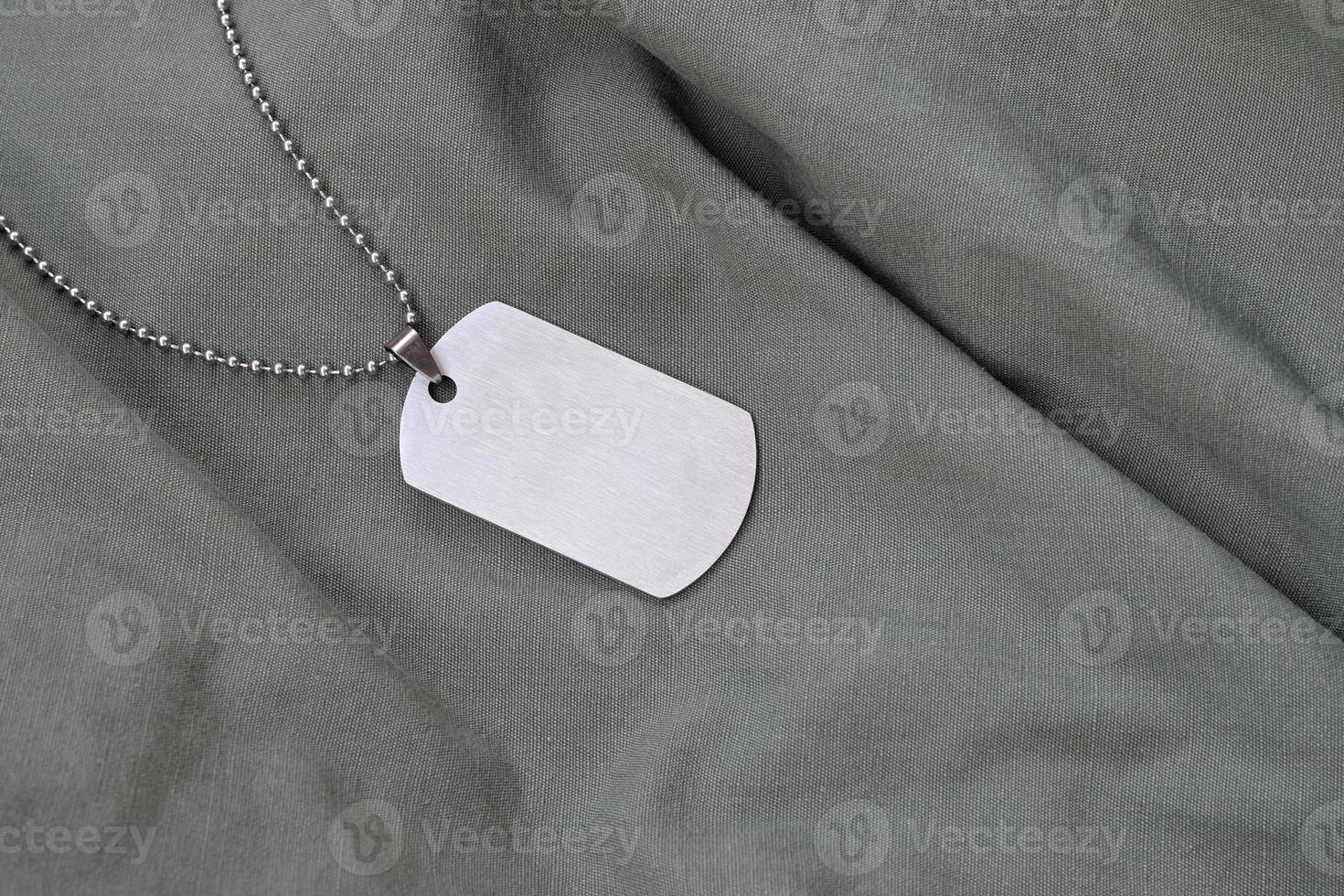 Silvery military beads with dog tag on dark green fatigue uniform photo