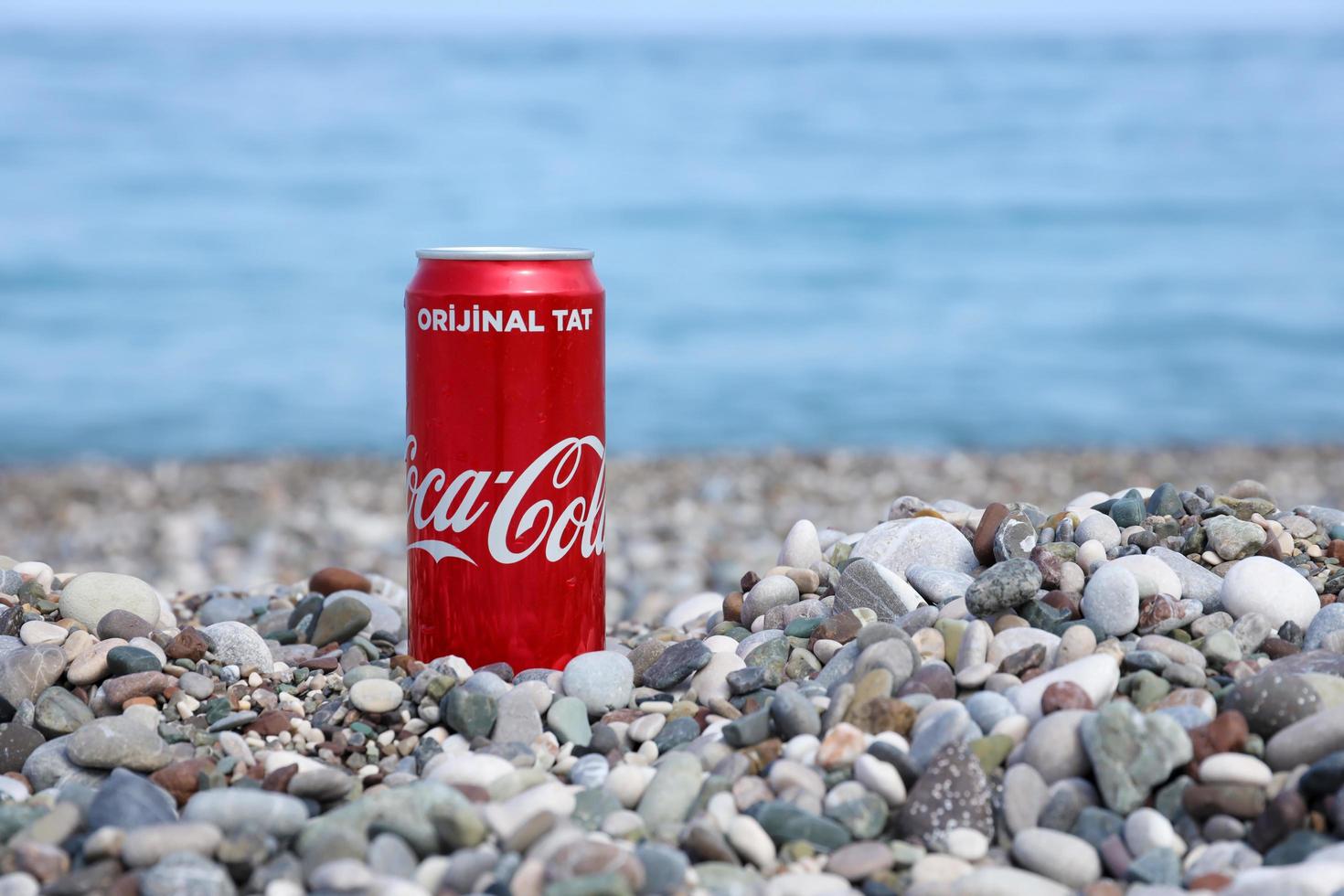 ANTALYA, TURKEY - MAY 18, 2022 Original Coca Cola red tin can lies on small round pebble stones close to sea shore. Coca-cola on turkish beach photo