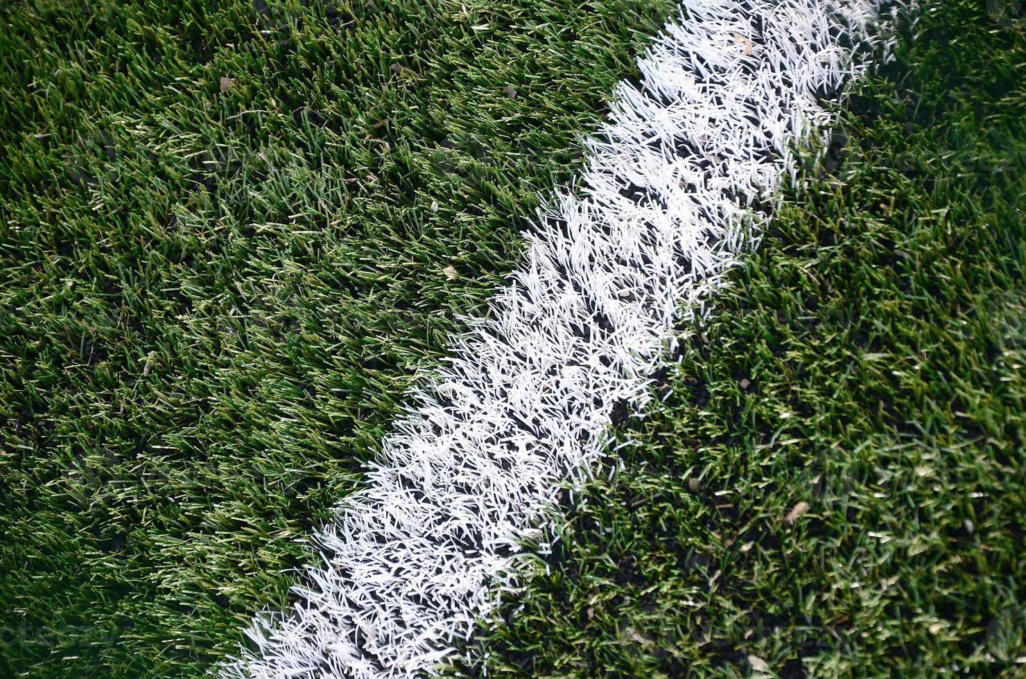 White stripe on a bright green artificial grass soccer field photo