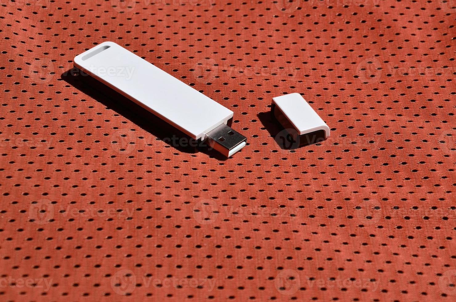 A modern portable USB wi-fi adapter is placed on the red sportswear made of polyester nylon fiber photo