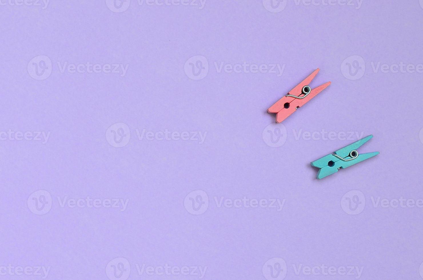 Two colored wooden pegs lie on texture background of fashion pastel violet color paper in minimal concept photo