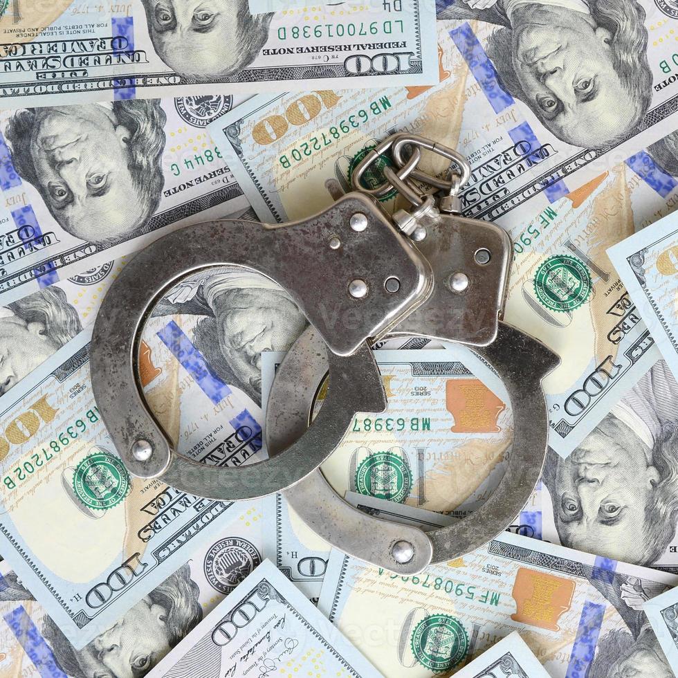 Silver police handcuffs lies on a many dollar bills photo