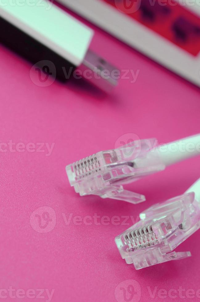 Internet router, portable USB wi-fi adapter and internet cable plugs lie on a bright pink background. Items required for internet photo