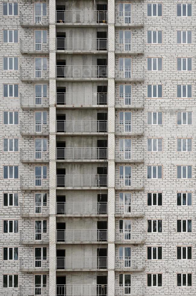 patrón texturizado de una pared de construcción de casas residenciales de piedra blanca rusa con muchas ventanas y balcón en construcción foto