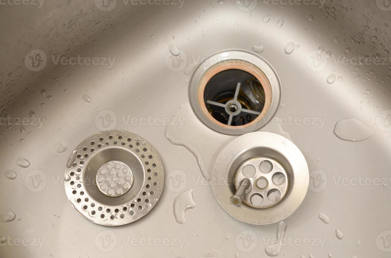 Silvery kitchen sink with a disassembled protective filter during the repair process photo