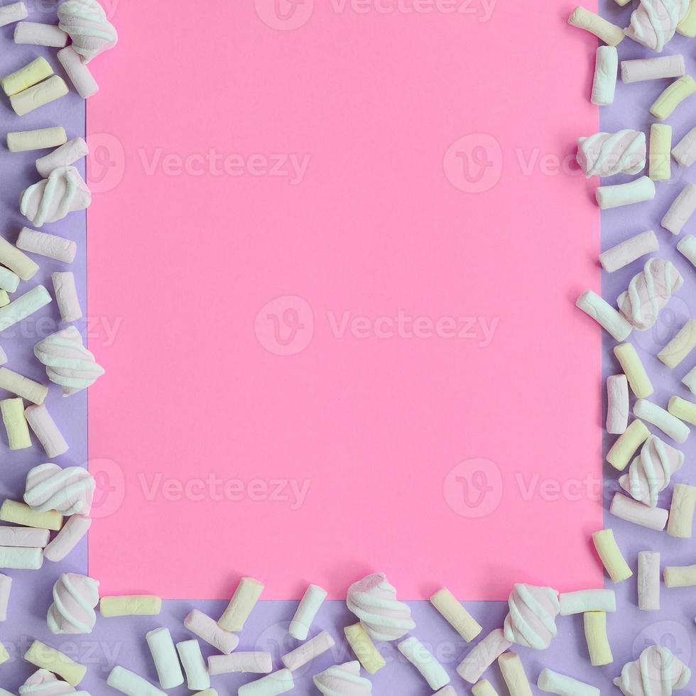 Colorful marshmallow laid out on violet and pink paper background. pastel creative textured framework. minimal photo
