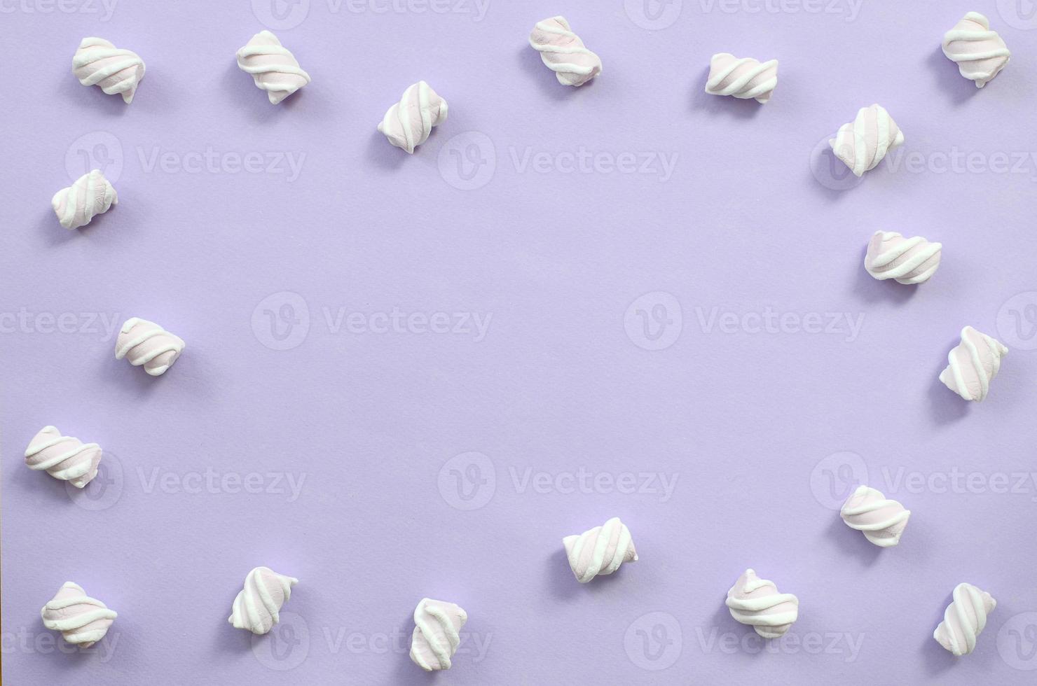Colorful marshmallow laid out on violet paper background. pastel creative textured framework. minimal photo