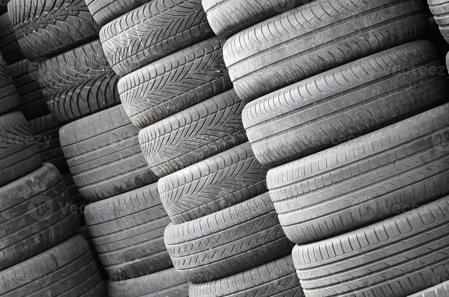Old used tires stacked with high piles in secondary car parts shop garage photo