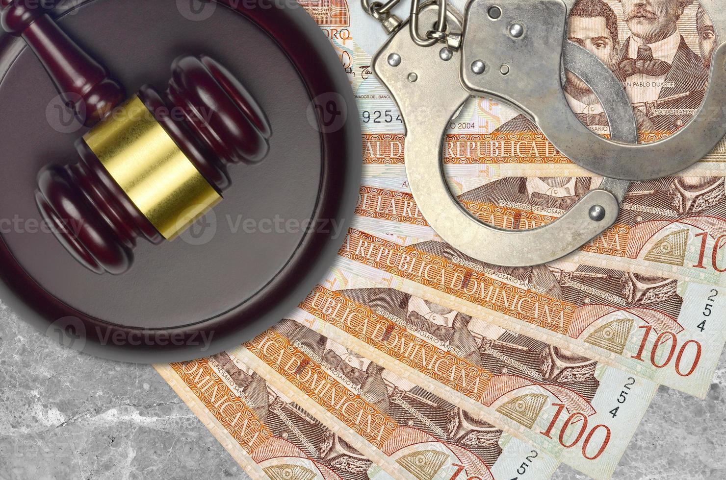 100 Dominican peso bills and judge hammer with police handcuffs on court desk. Concept of judicial trial or bribery. Tax avoidance photo